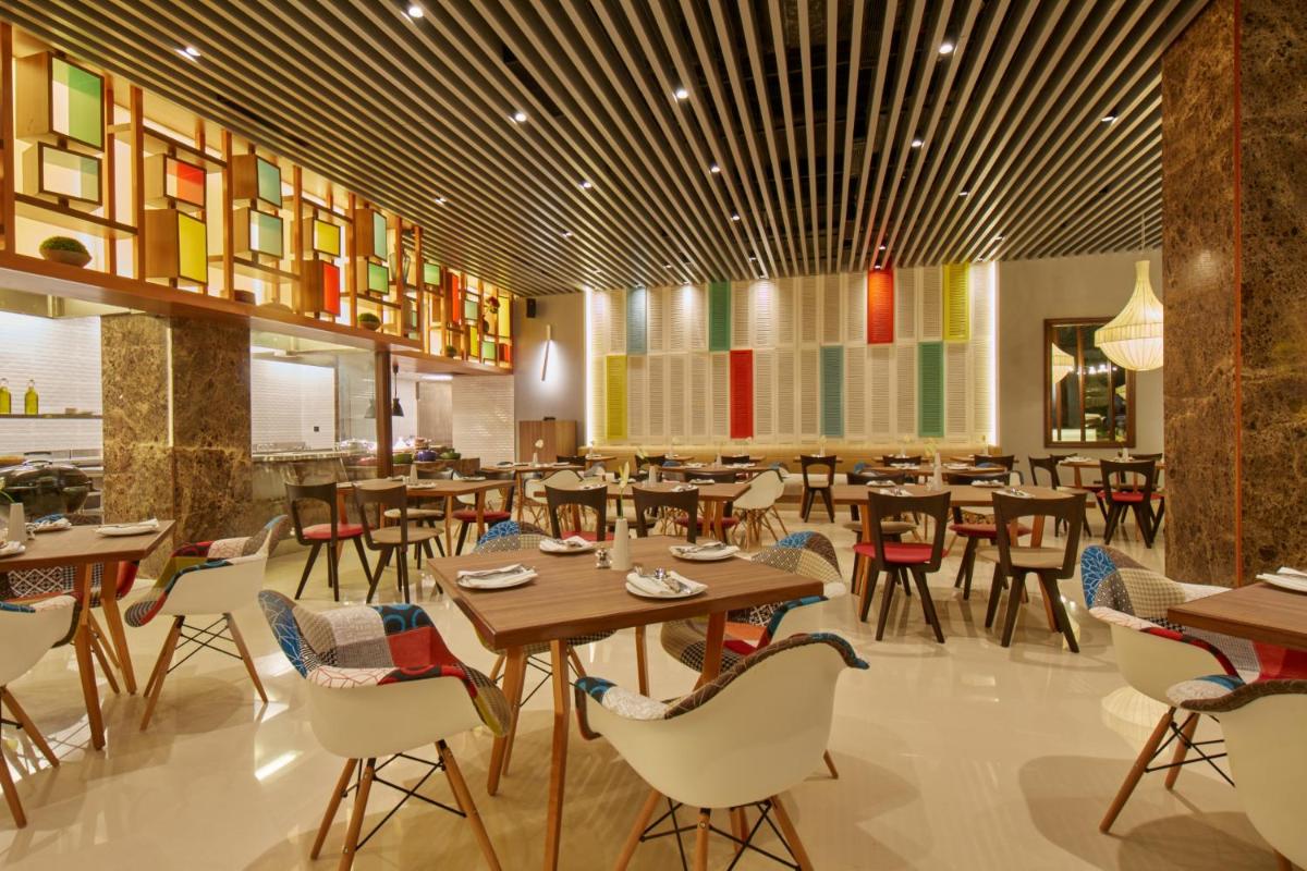 a restaurant with tables and chairs in a room at Hotel Royal Orchid Bangalore in Bengaluru