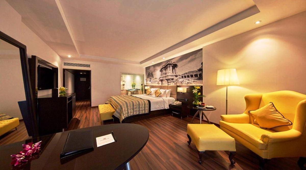 a hotel room with a bed and a living room at Hotel Royal Orchid Bangalore in Bengaluru