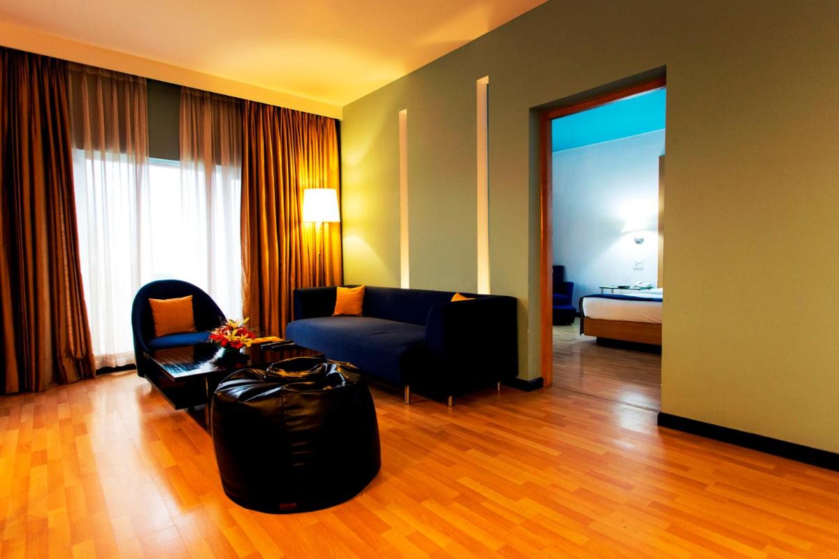 a living room with a couch and a chair at Hotel Royal Orchid Bangalore in Bengaluru
