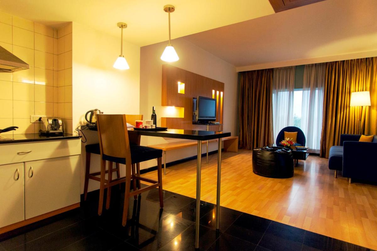 a hotel room with a kitchen and a living room at Hotel Royal Orchid Bangalore in Bengaluru