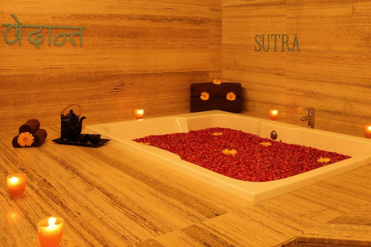 a bath tub filled with red peppers in a room with candles at The Metropolitan Hotel & Spa New Delhi in New Delhi
