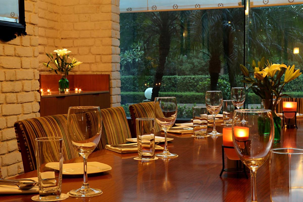 a long wooden table with wine glasses and candles at The Metropolitan Hotel & Spa New Delhi in New Delhi