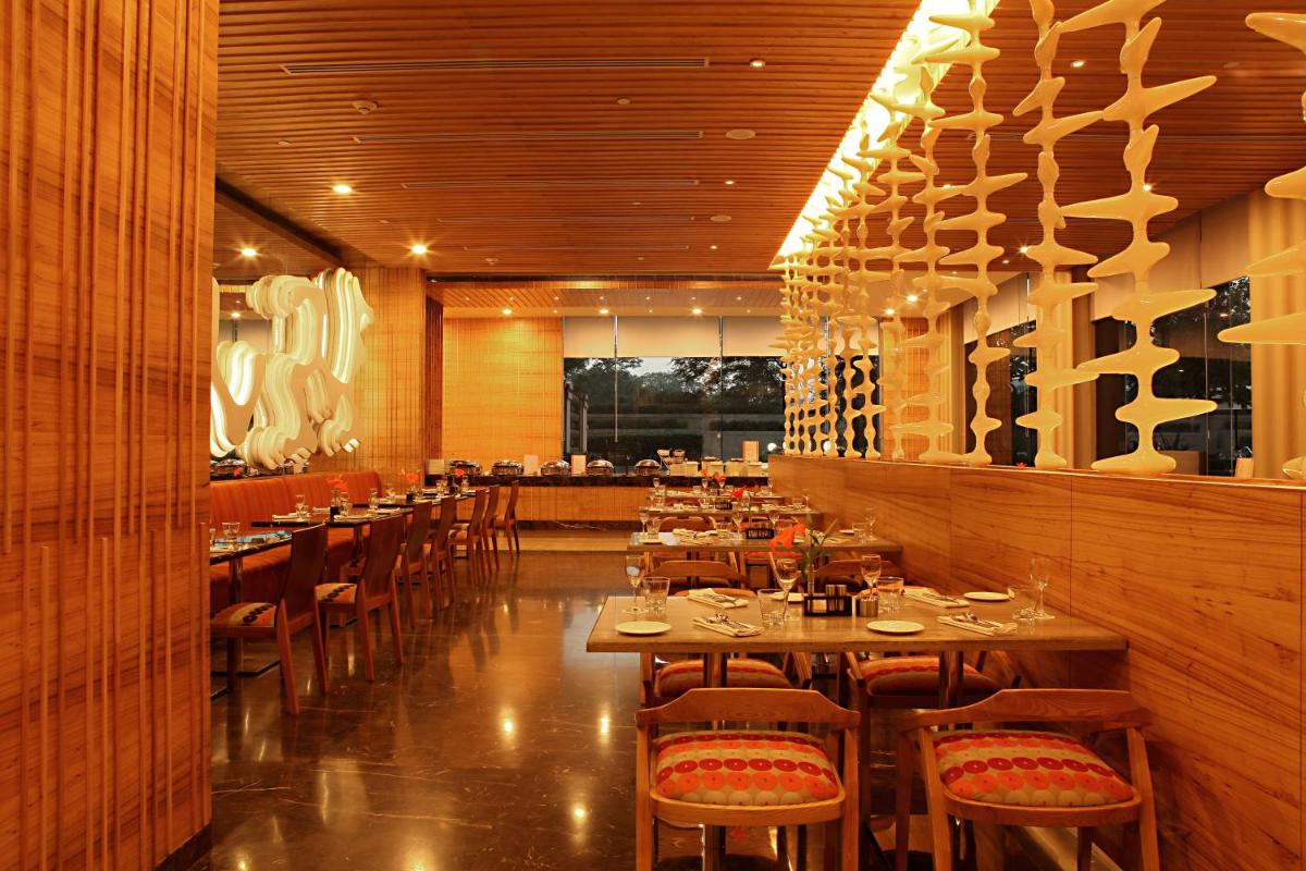 a restaurant with wooden walls and tables and chairs at The Metropolitan Hotel & Spa New Delhi in New Delhi