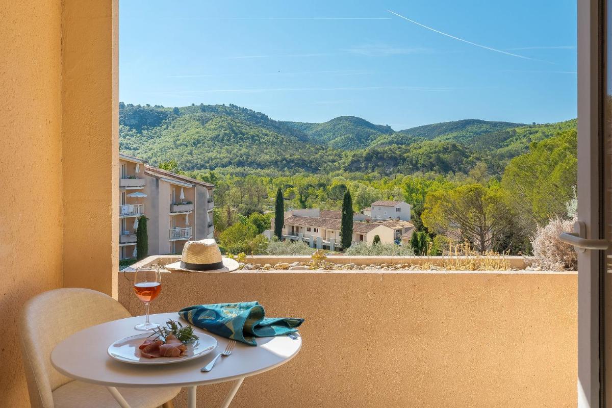 une table avec une assiette de nourriture et un verre de vin dans l'établissement Résidence les Grands Pins, à Gréoux-les-Bains