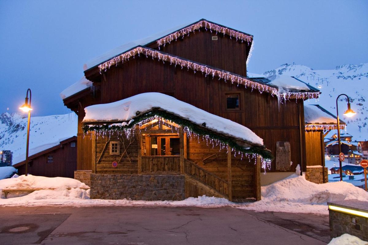 un bâtiment recouvert de neige avec des lumières allumées dans l'établissement Résidences Village Montana by Les Etincelles, à Tignes