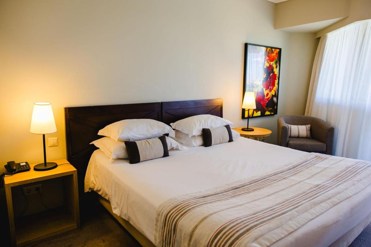 um quarto com uma cama com dois abajures e uma cadeira em Evora Hotel em Évora mais 76 fotografias