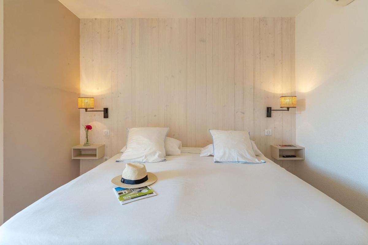 un lit avec un chapeau et un magazine dessus dans l'établissement Résidence les Grands Pins, à Gréoux-les-Bains 22 autres photos