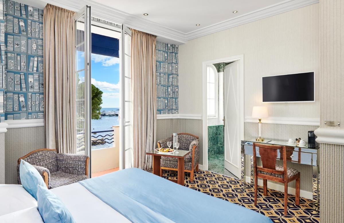 une chambre d'hôtel avec un lit, un bureau et une fenêtre dans l'établissement Hôtel Belles Rives, à Juan-les-Pins