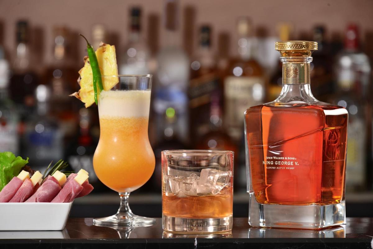 a bottle of alcohol next to a glass ofociate at Fortune Miramar, Goa - Member ITC Hotels' Group in Panaji a bottle of alcohol next to a glass ofociate at Fortune Miramar, Goa - Member ITC Hotels' Group in Panaji