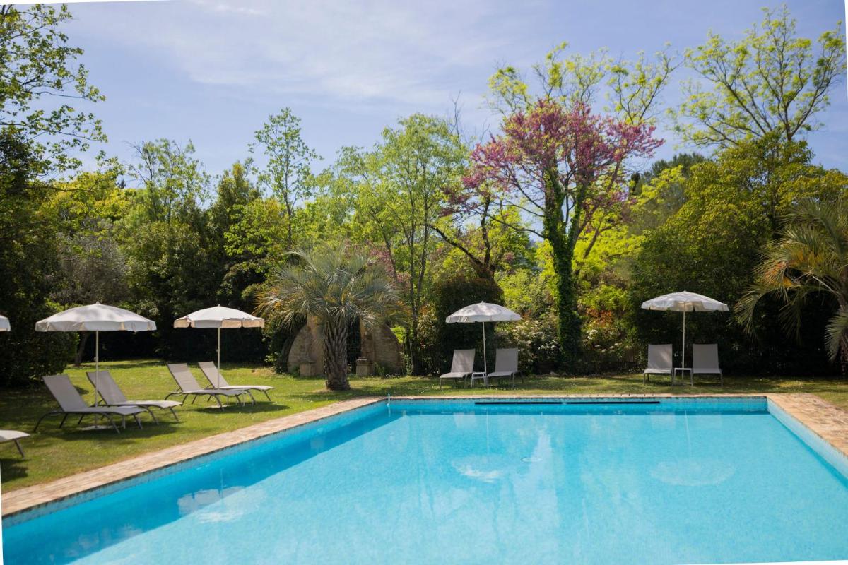 une piscine avec chaises longues et parasols dans l'établissement Hôtel - Restaurant & Spa La Magdeleine - Mathias Dandine, à Gémenos