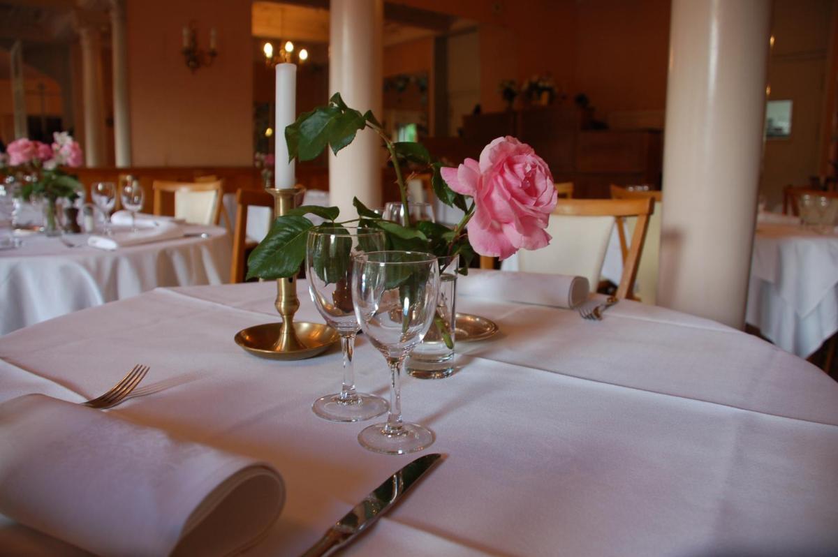 une table avec des verres et une rose rose sur elle dans l'établissement Logis Hôtel Regina, à La Bourboule