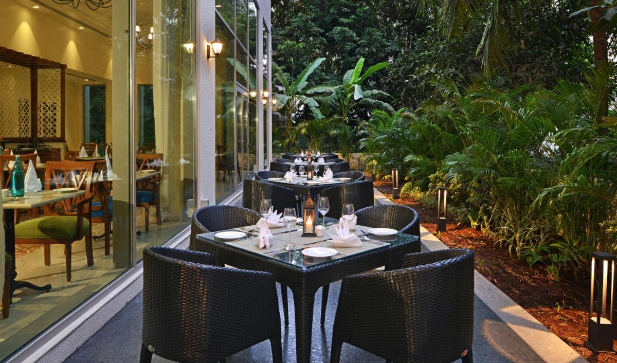 a dining room with tables and chairs and trees at Fortune Miramar, Goa - Member ITC Hotels' Group in Panaji a dining room with tables and chairs and trees at Fortune Miramar, Goa - Member ITC Hotels' Group in Panaji