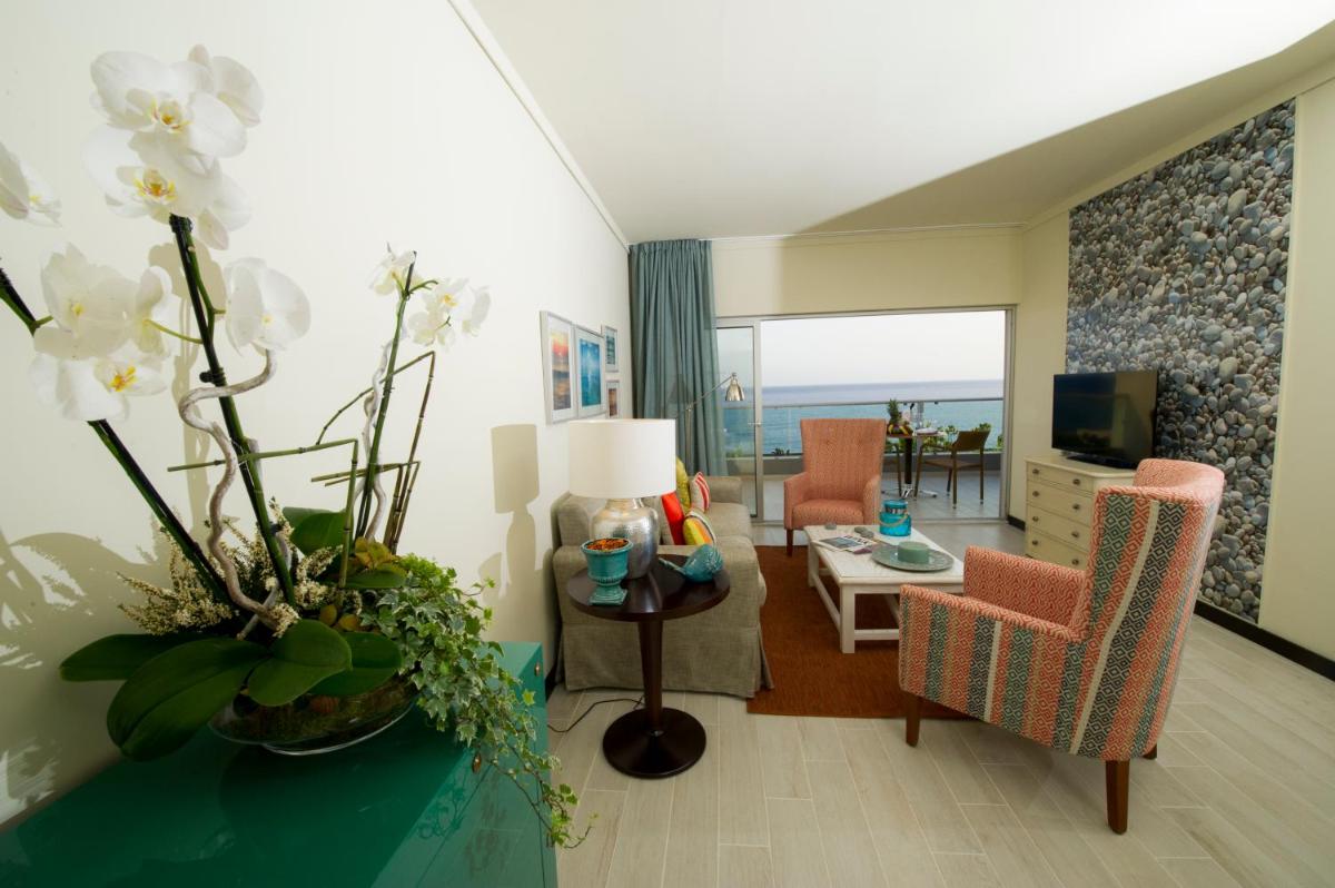 uma sala de estar com um sofá e uma mesa com flores em Pestana Madeira Beach Club no Funchal