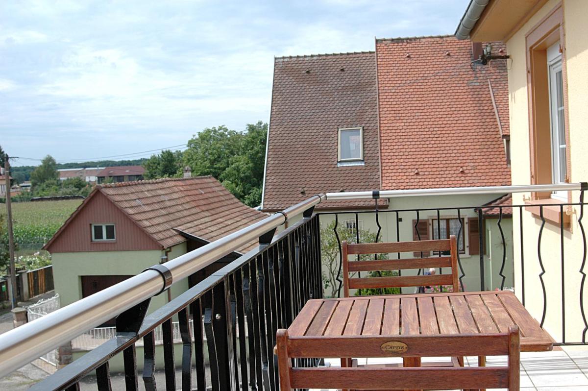 - un balcon avec un banc en bois et un bâtiment dans l'établissement Résidence Les Cigogneaux, à Ostheim - un balcon avec un banc en bois et un bâtiment dans l'établissement Résidence Les Cigogneaux, à Ostheim