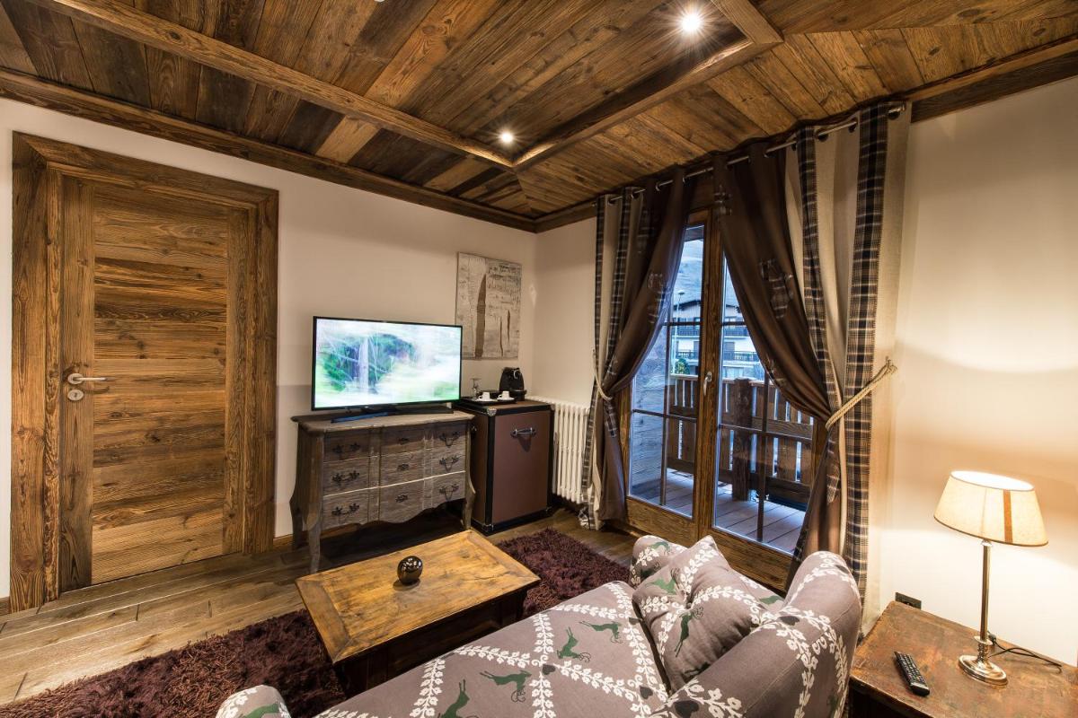 un salon avec un canapé et une télévision dans l'établissement Le Chalet Blanc, à Megève