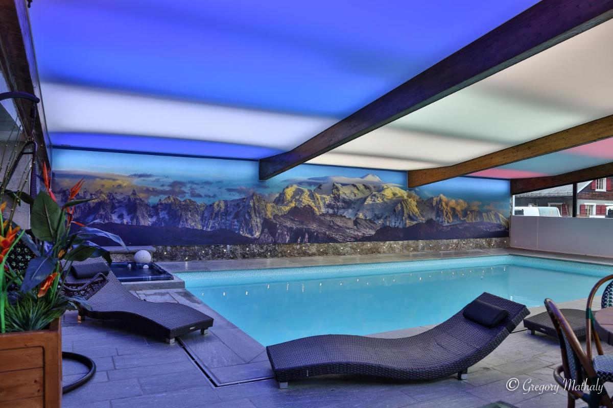 une piscine avec des chaises et une fresque de montagne dans l'établissement Hotel L'Equipe, à Morzine