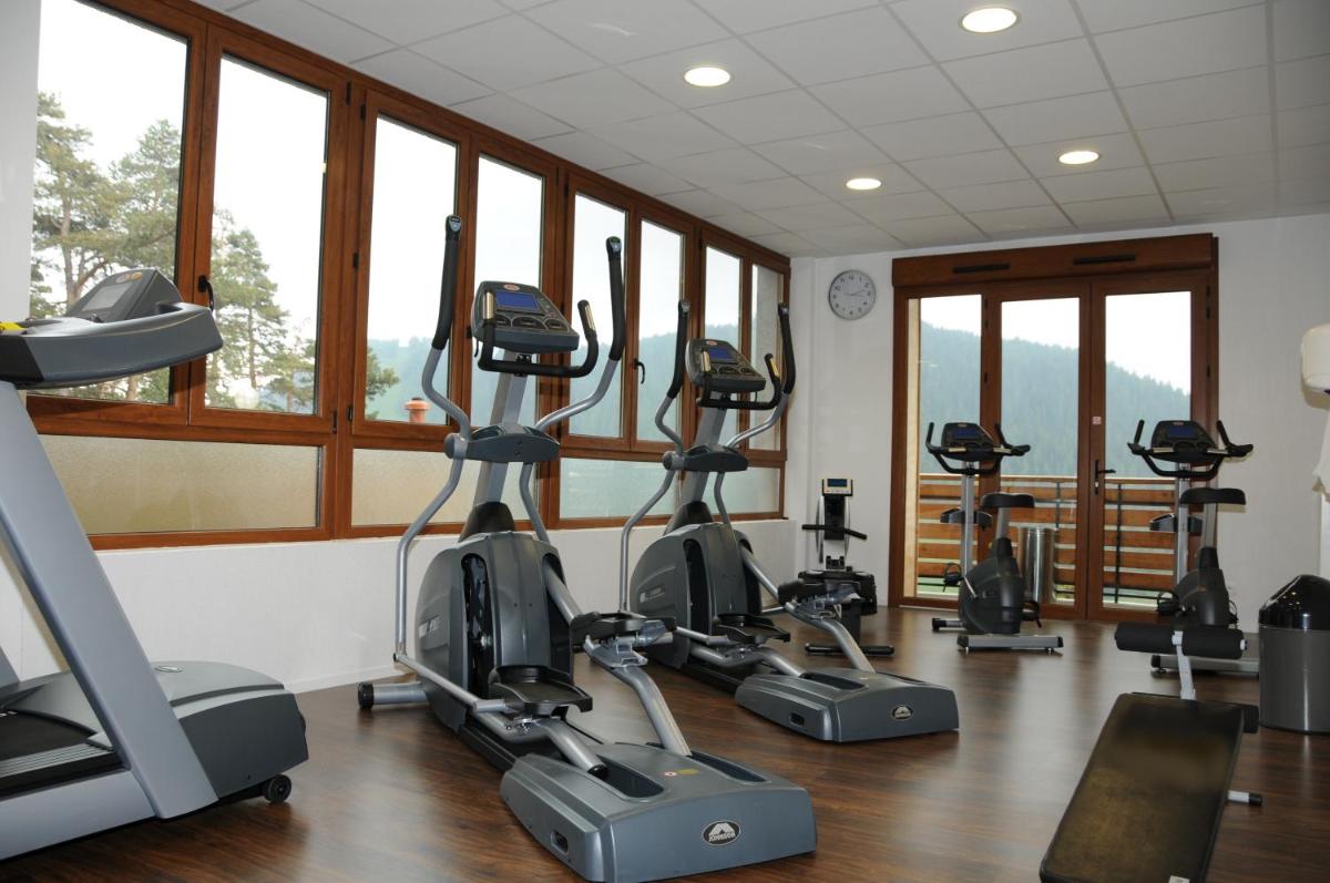 une salle de sport avec plusieurs vélos d'exercice dans une pièce avec fenêtres dans l'établissement Adrechas Mercantour, à La Colmiane