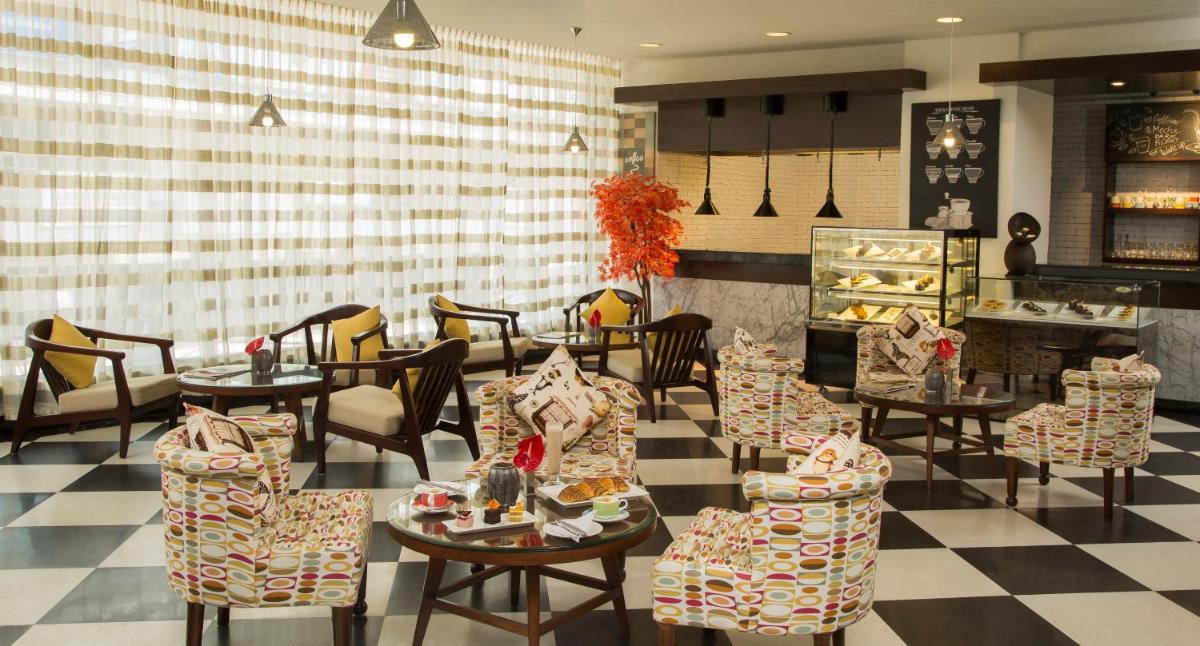 a restaurant with tables and chairs and a checkered floor at The Raviz Calicut in Kozhikode