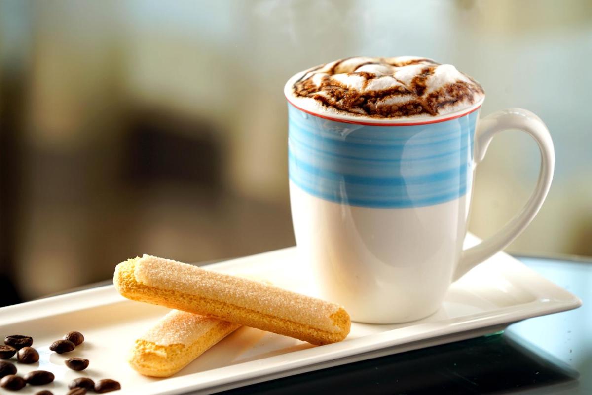 a cup of coffee and a cookie on a plate at The Raviz Calicut in Kozhikode