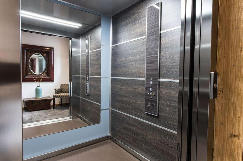 un couloir avec une porte coulissante en verre et un miroir dans l'établissement Le Chalet Blanc, à Megève un couloir avec une porte coulissante en verre et un miroir dans l'établissement Le Chalet Blanc, à Megève
