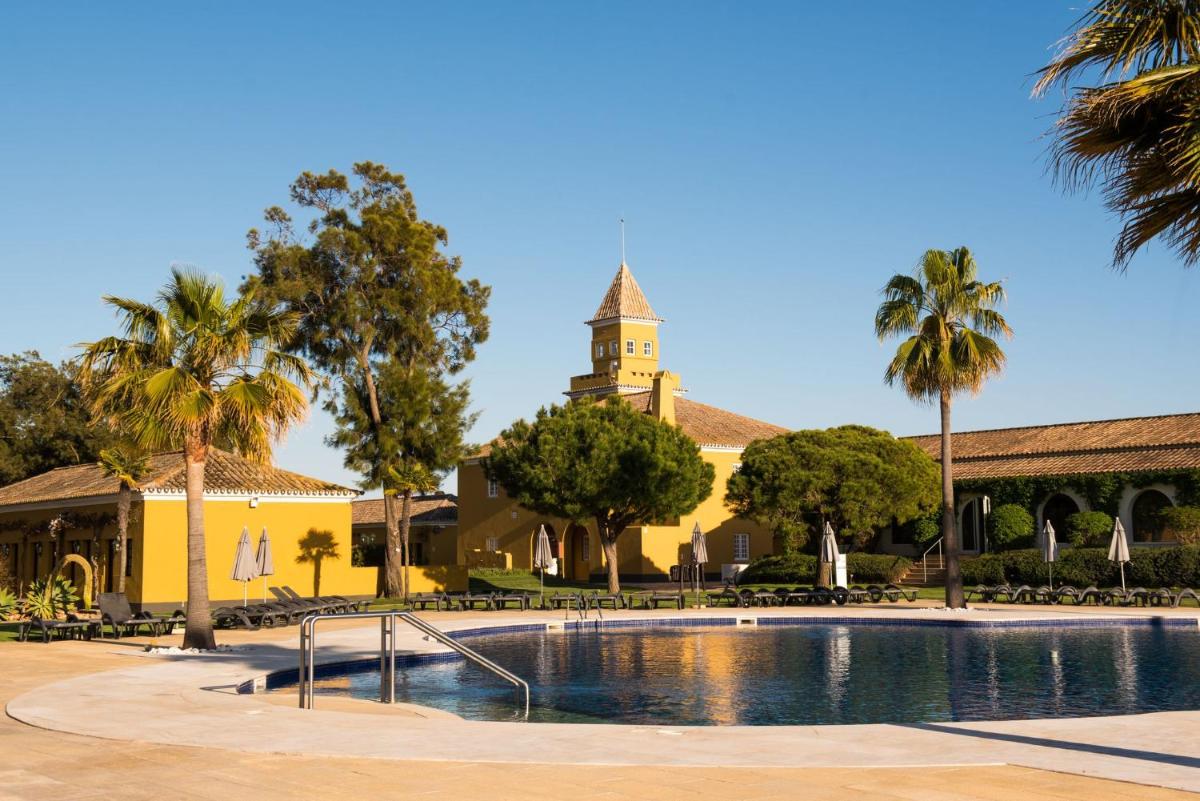 um edifício com uma torre de relógio e uma piscina em Vila Gale Albacora em Tavira