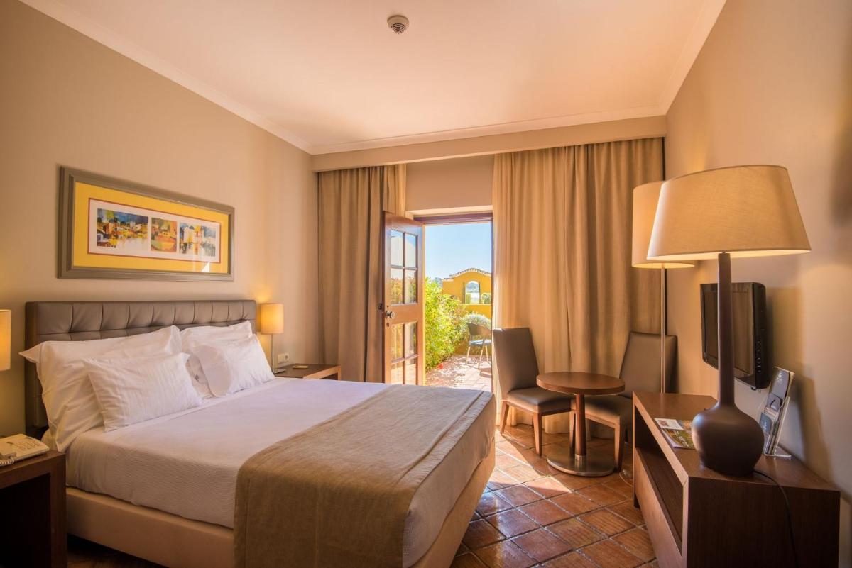 um quarto de hotel com uma cama e uma porta de vidro deslizante em Vila Gale Albacora em Tavira