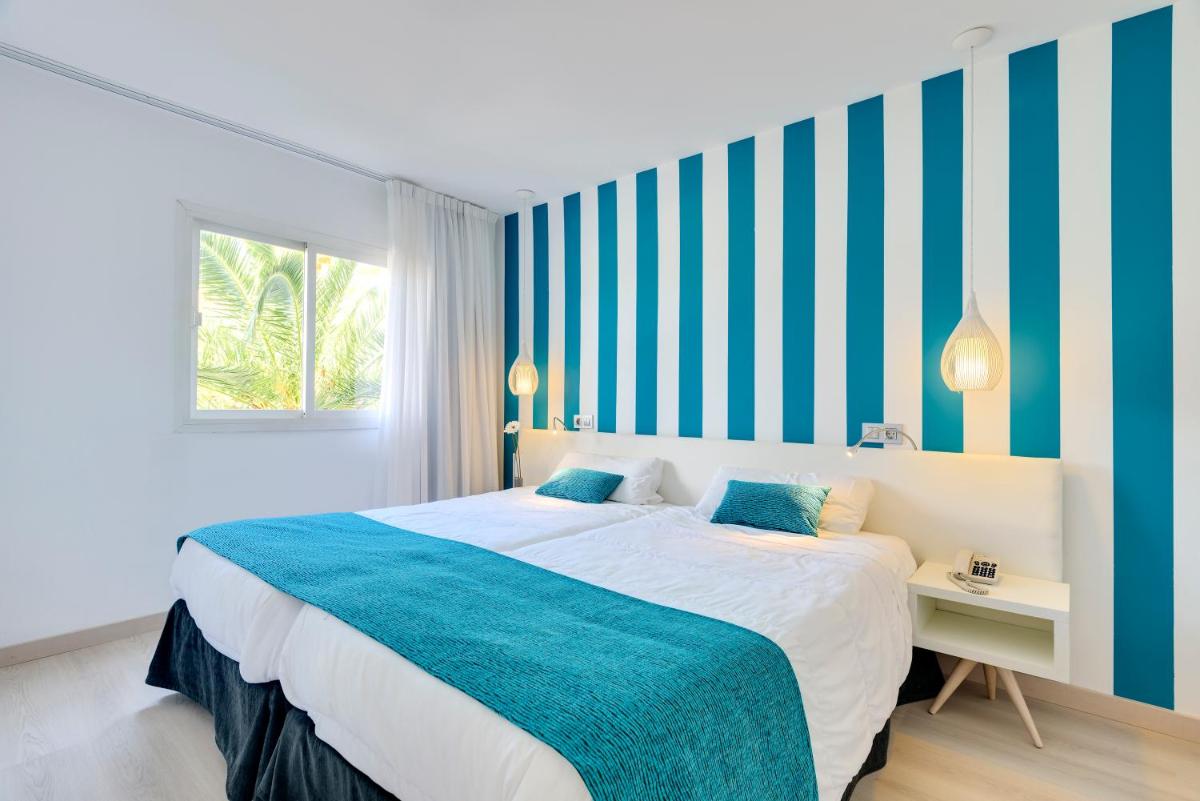 1 dormitorio con 1 cama grande con rayas azules y blancas en Alcudia Garden Aparthotel, en Puerto de Alcudia 78 fotos más