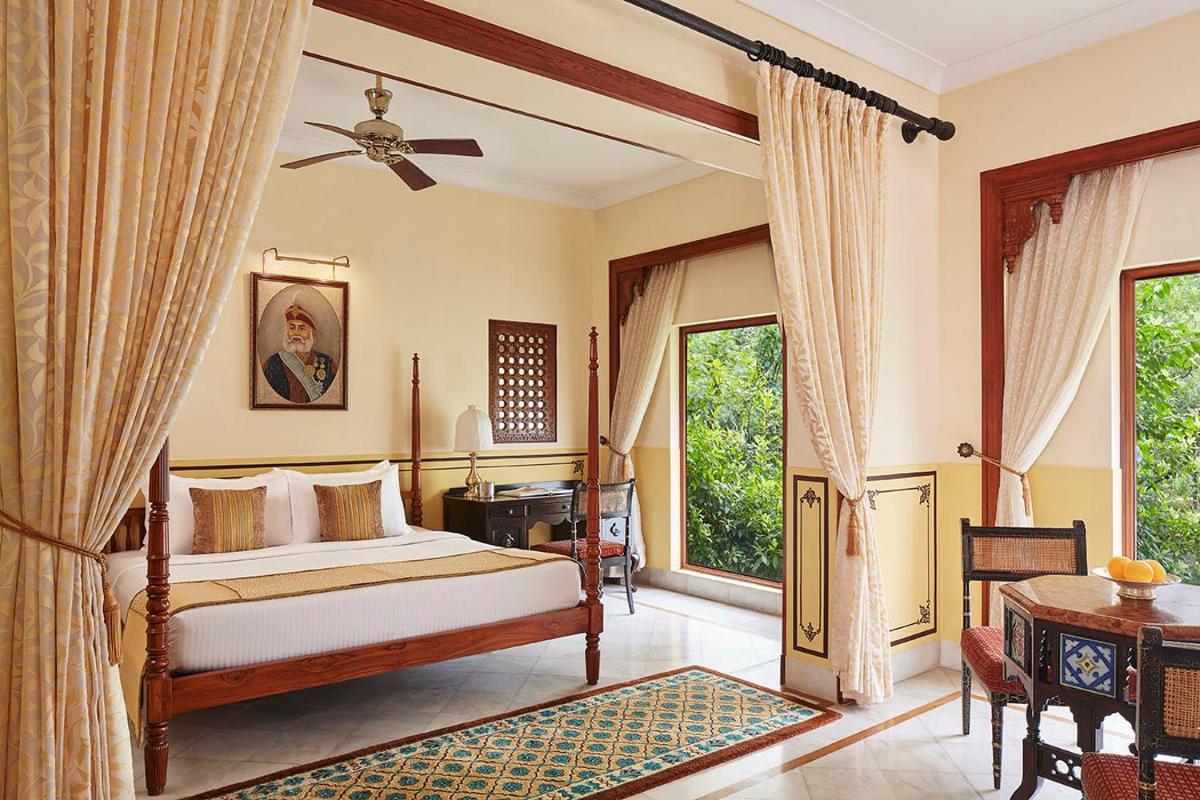 a bedroom with a bed and a table and windows at Jai Mahal Palace in Jaipur