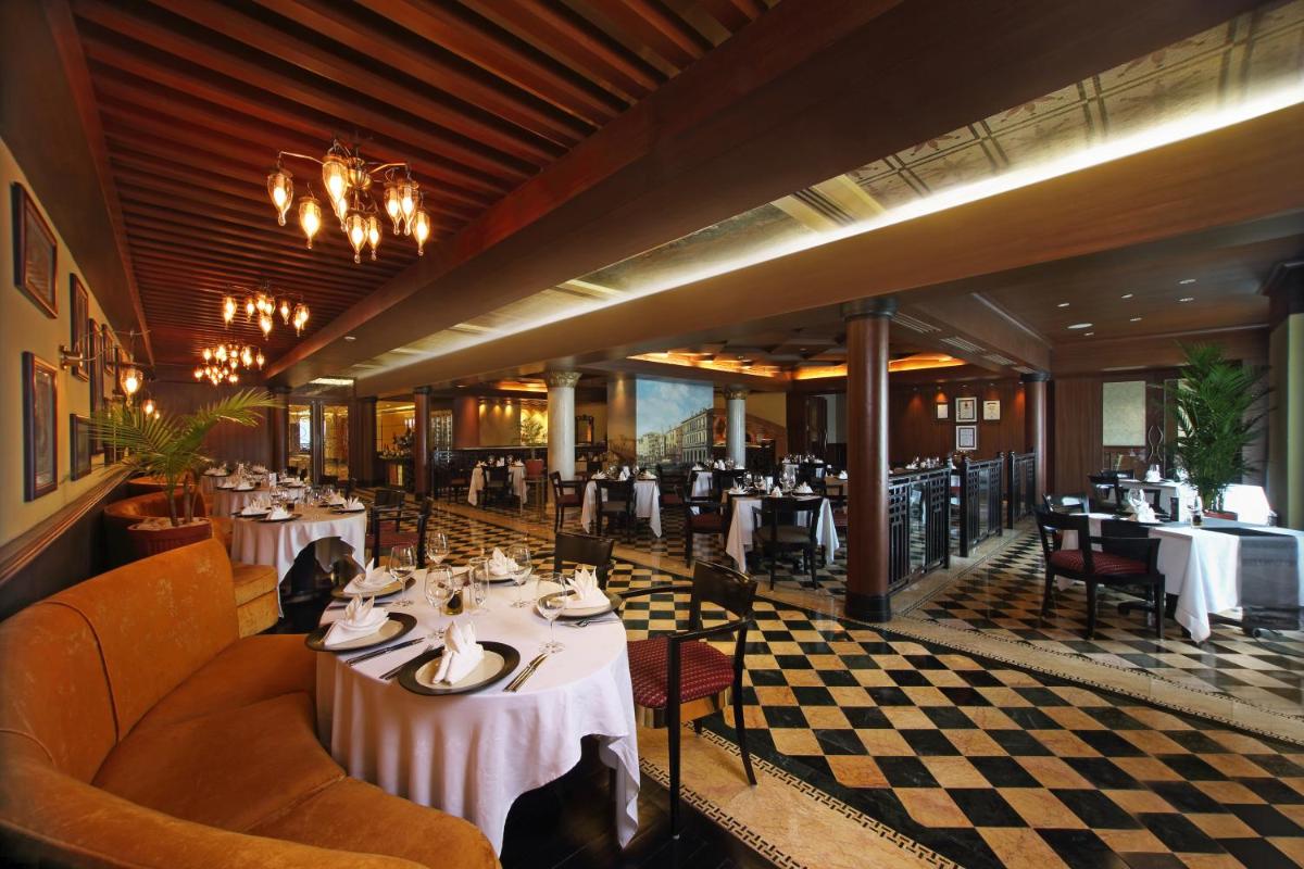 a restaurant with white tables and chairs and a checkered floor at Gokulam Grand Hotel & Spa Bangalore in Bengaluru a restaurant with white tables and chairs and a checkered floor at Gokulam Grand Hotel & Spa Bangalore in Bengaluru