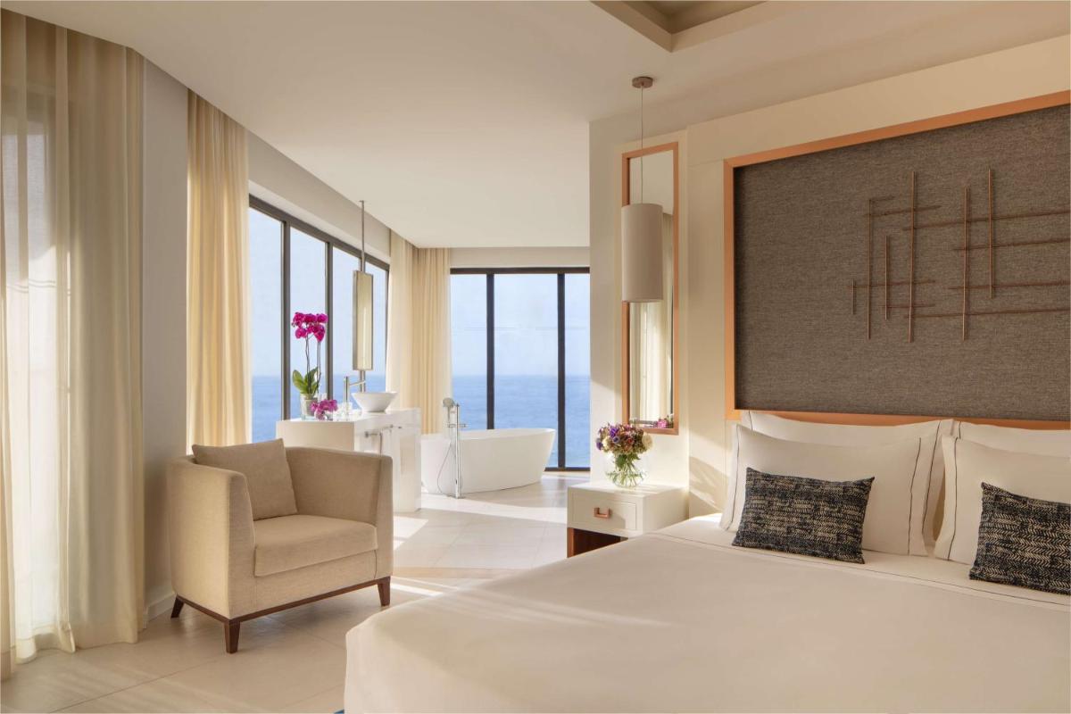 um quarto de hotel com uma cama e uma cadeira em Tivoli Carvoeiro em Carvoeiro um quarto de hotel com uma cama e uma cadeira em Tivoli Carvoeiro em Carvoeiro