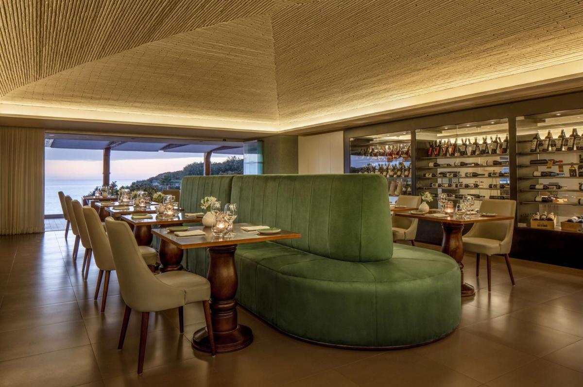 um restaurante com uma mesa comprida com cadeiras e garrafas de vinho em Tivoli Carvoeiro em Carvoeiro