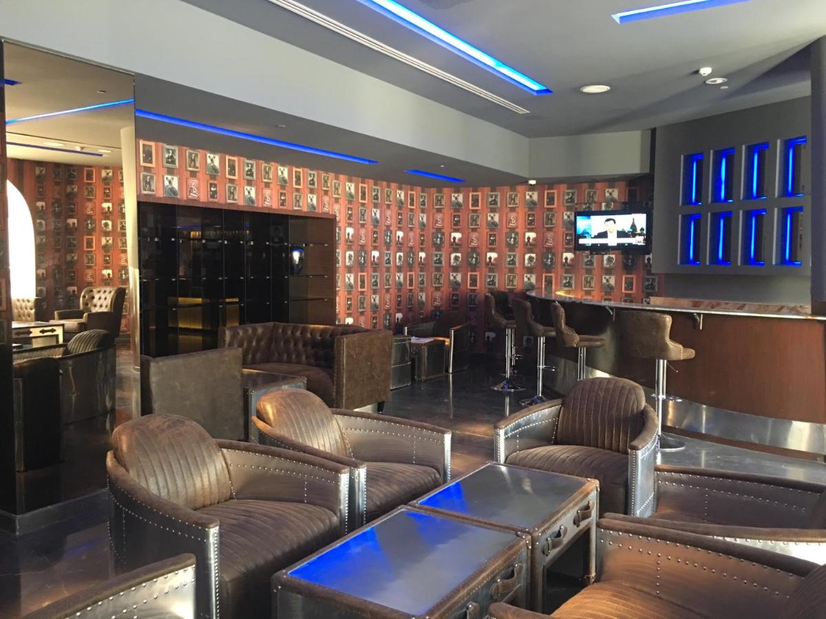 a bar with leather chairs and tables in a room at Radisson Blu Atria Bengaluru in Bengaluru a bar with leather chairs and tables in a room at Radisson Blu Atria Bengaluru in Bengaluru