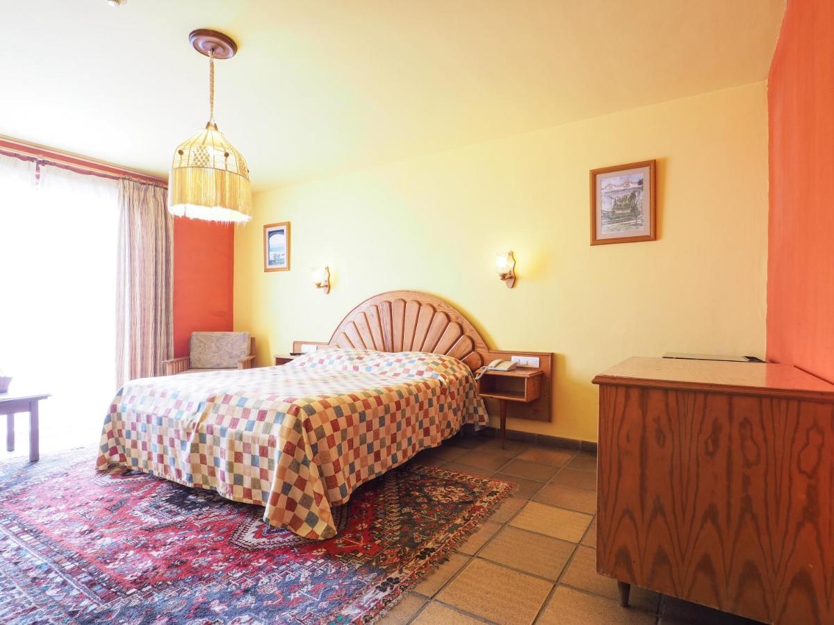 Una habitación de hotel con una cama, una mesa y un televisor. en Hotel La Palma Romántica, en Barlovento