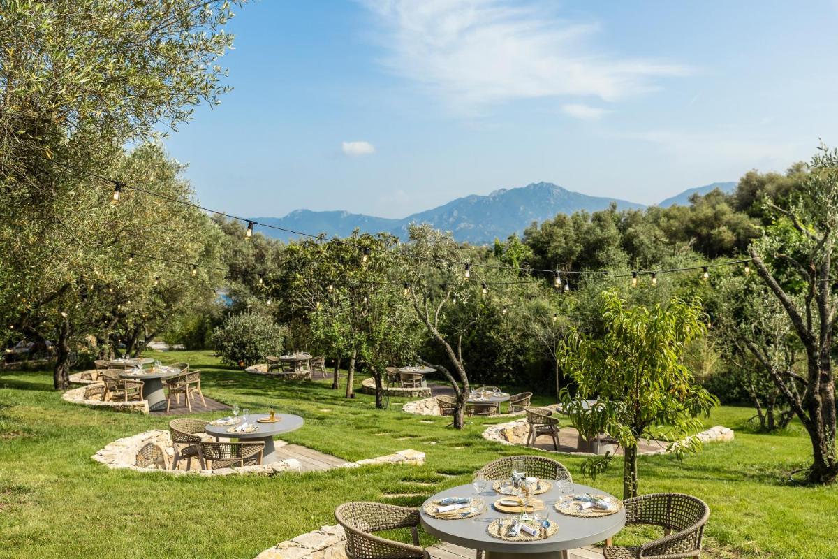 une aire de pique-nique avec des tables et des chaises dans un parc dans l'établissement L'Hostellerie du Moulin des Oliviers, à Olmeto 53 autres photos