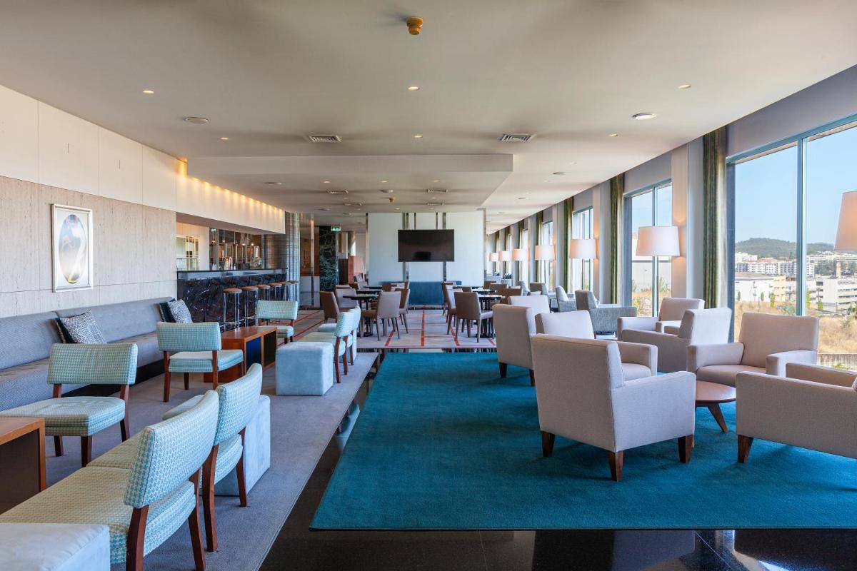 uma sala de espera com cadeiras, mesas e janelas em Hotel de Guimaraes Business & SPA em Guimarães