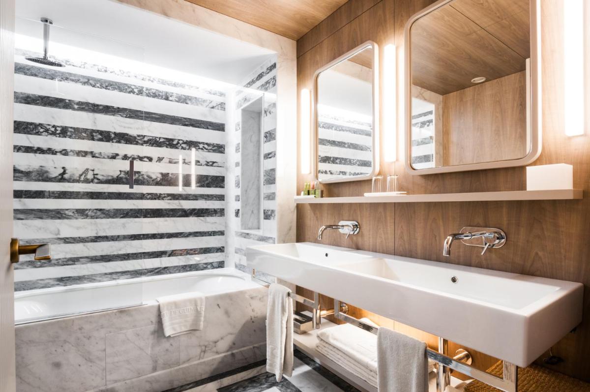 um banheiro com pia branca e banheira em Hotel de Guimaraes Business & SPA em Guimarães