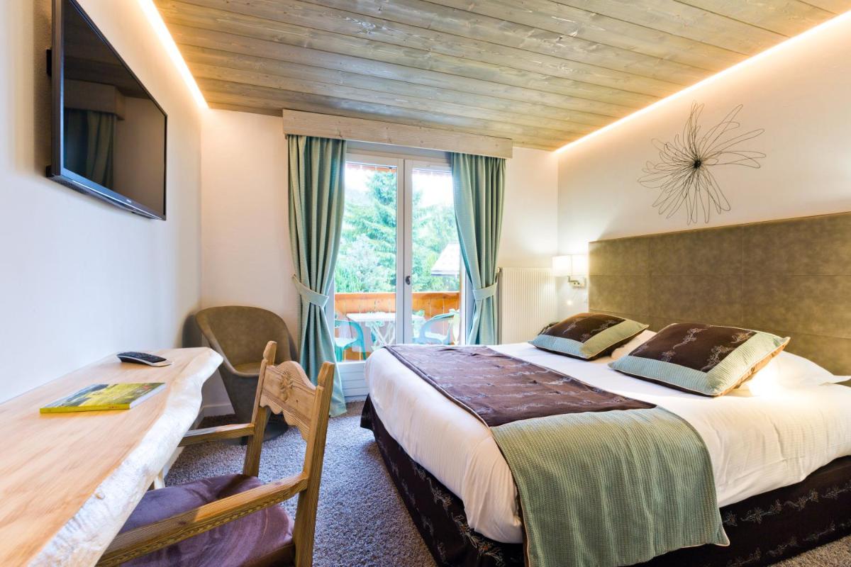 une chambre avec un lit, un bureau et une télévision dans l'établissement Les Gentianettes Hotel & Spa, à La Chapelle-dʼAbondance 118 autres photos
