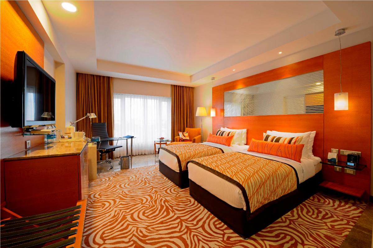 a hotel room with two beds and a desk at Radisson Blu Hotel Ahmedabad in Ahmedabad