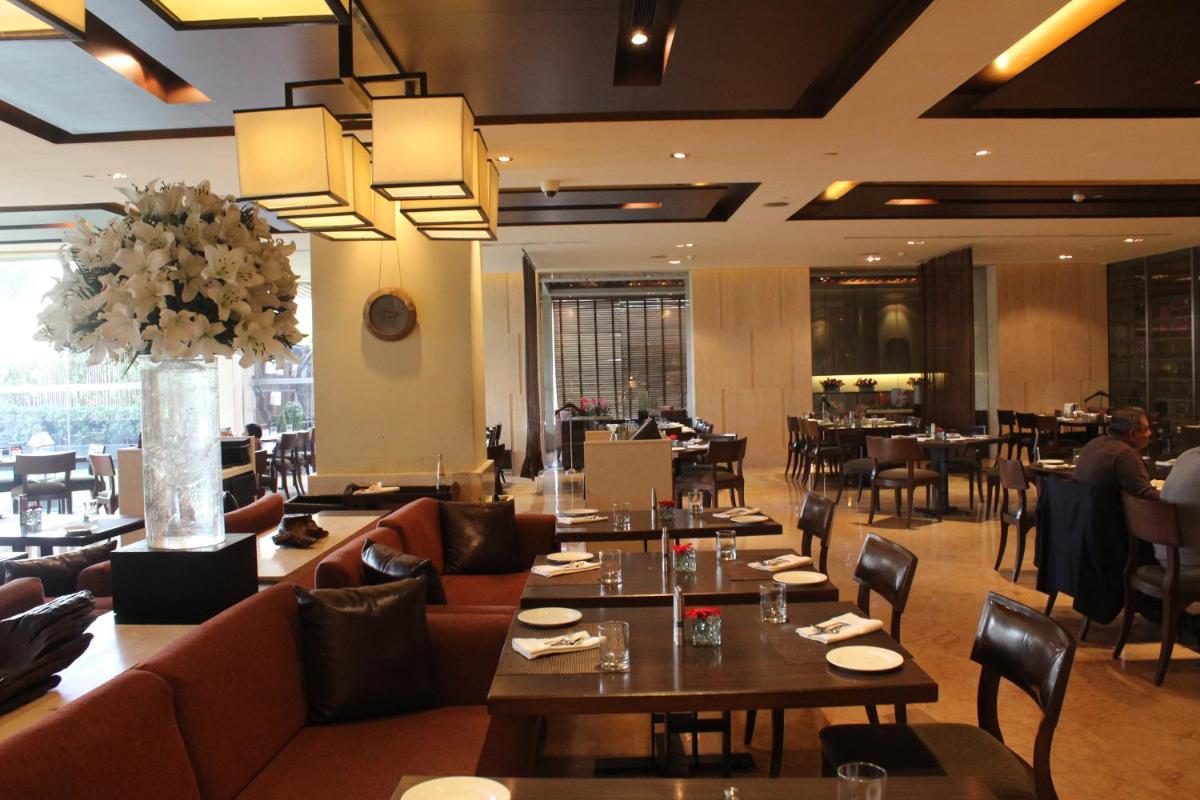 a restaurant with couches and tables and chairs at The LaLiT New Delhi in New Delhi