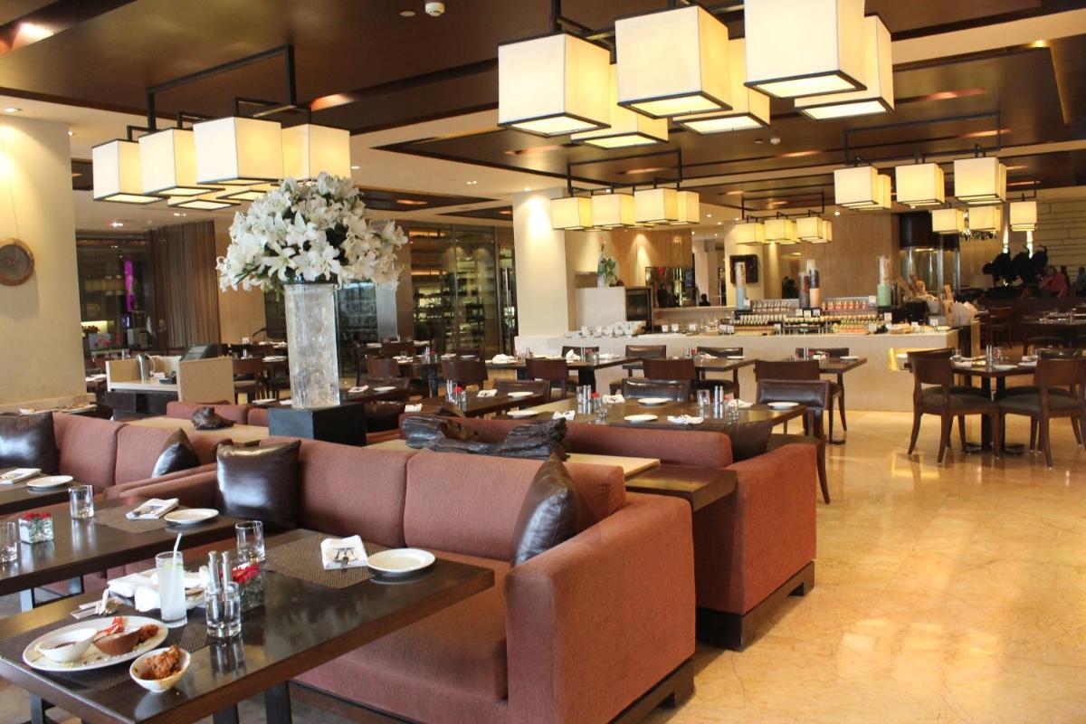 a restaurant with brown couches and tables and chairs at The LaLiT New Delhi in New Delhi
