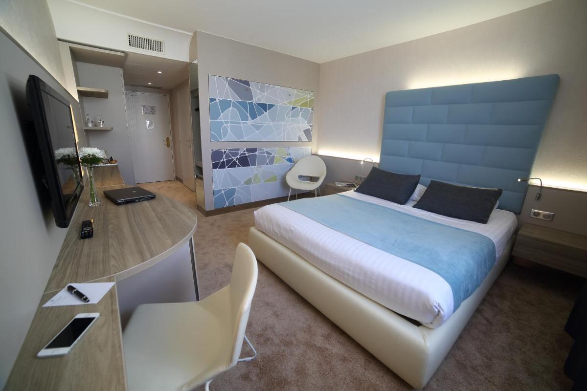 une chambre d'hôtel avec un grand lit et un bureau dans l'établissement Hotel Plaza - site du Futuroscope, à Chasseneuil-du-Poitou