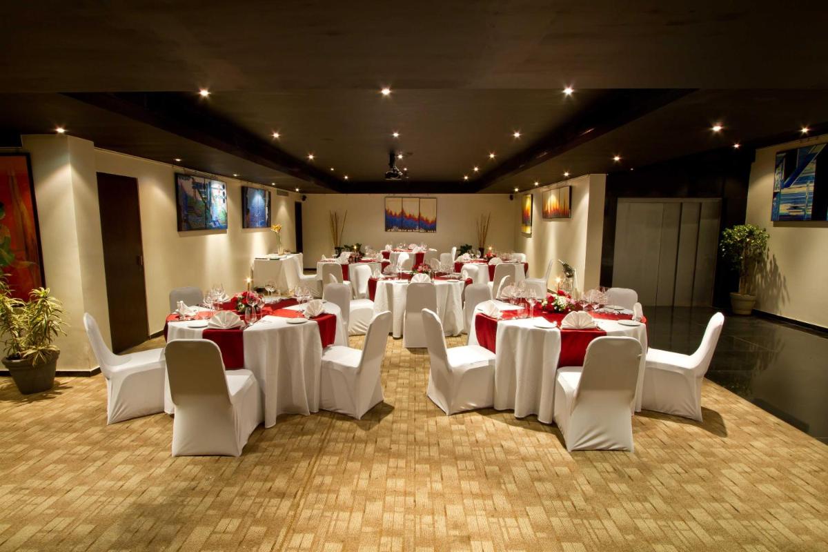 a room with white tables and white chairs and tablesearcher at Svenska Design Hotel in Mumbai