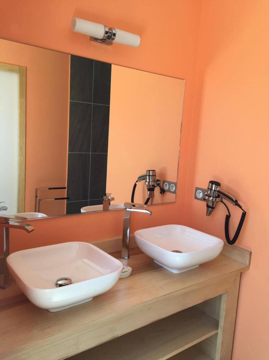 une salle de bains avec deux lavabos et un grand miroir dans l'établissement Hôtel du Bout du Monde, à Saint-Flour
