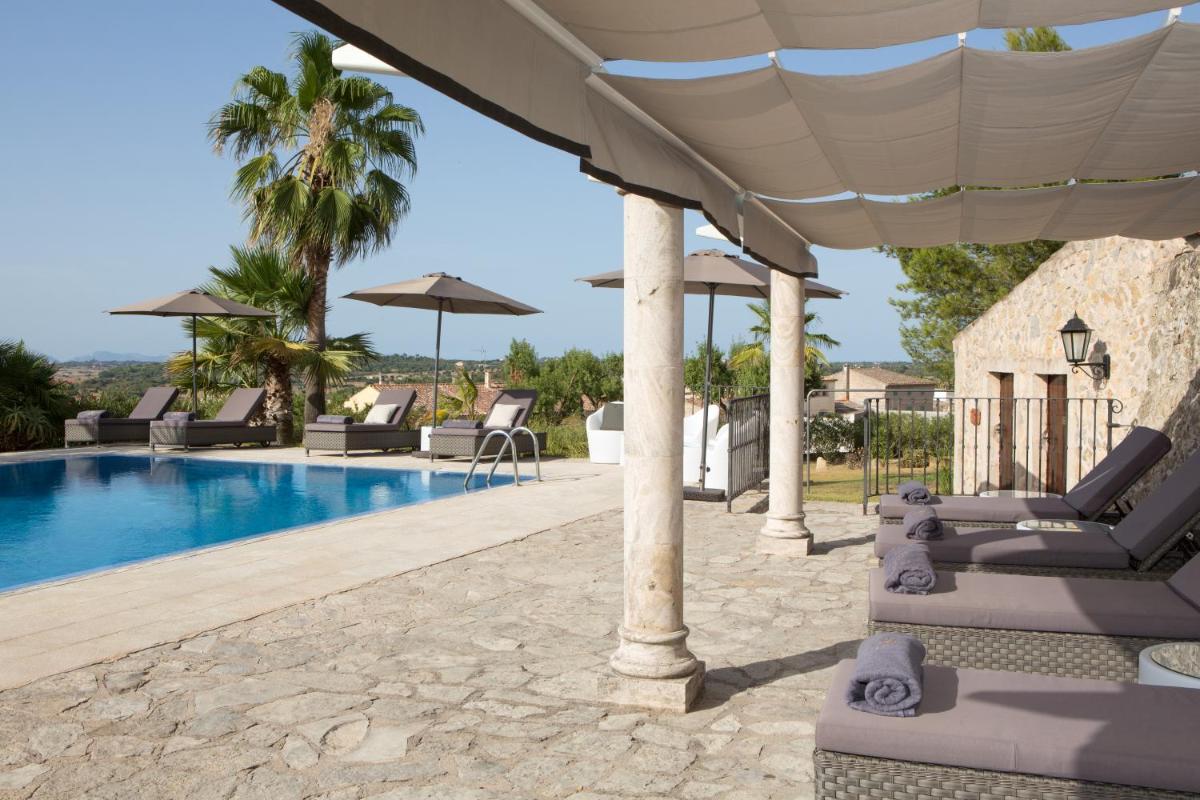 una piscina con sillas y sombrillas junto a un complejo en Casa Font i Roig, en Maria de la Salut
