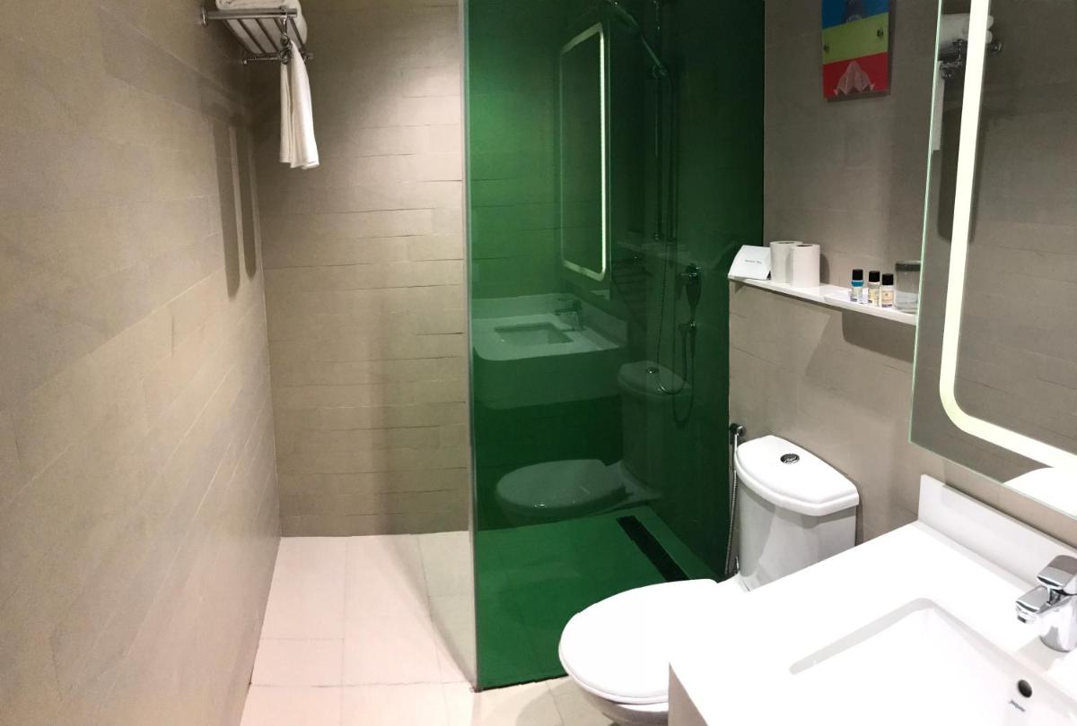a bathroom with a toilet and a green shower at Park Inn by Radisson,South Delhi in New Delhi a bathroom with a toilet and a green shower at Park Inn by Radisson,South Delhi in New Delhi