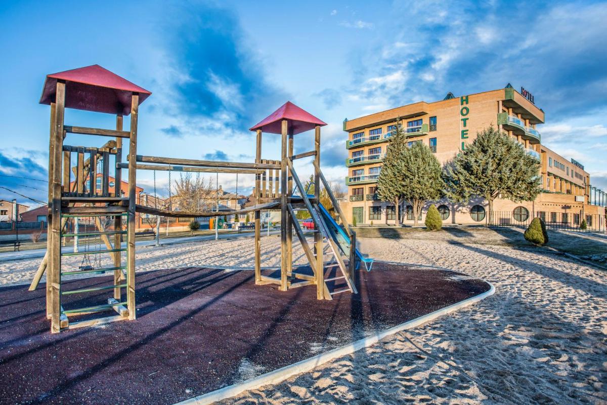 Un parque infantil con un tobogán frente a un edificio. en Hotel Spa Rio Ucero, en El Burgo de Osma