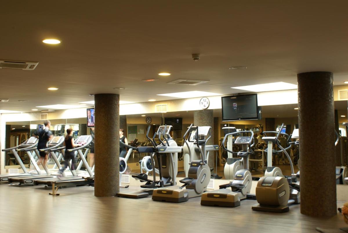 un gimnasio con muchas máquinas de correr y un reloj en Cumbria Spa Hotel 3* Sup, en Ciudad Real