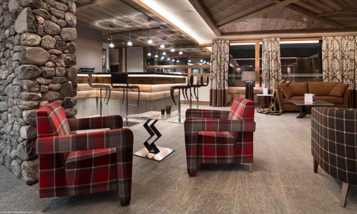 - un hall avec des chaises et un mur en pierre dans l'établissement MGM Hôtels & Résidences - Résidence Le Cristal de Jade, à Chamonix-Mont-Blanc