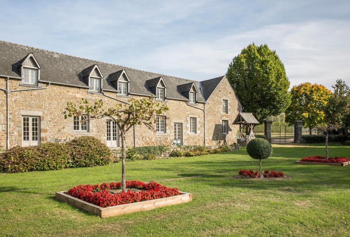 un grand bâtiment en briques avec un arbre dans une cour dans l'établissement Hotel de L'Abbaye Le Tronchet - Handwritten Collection, au Tronchet