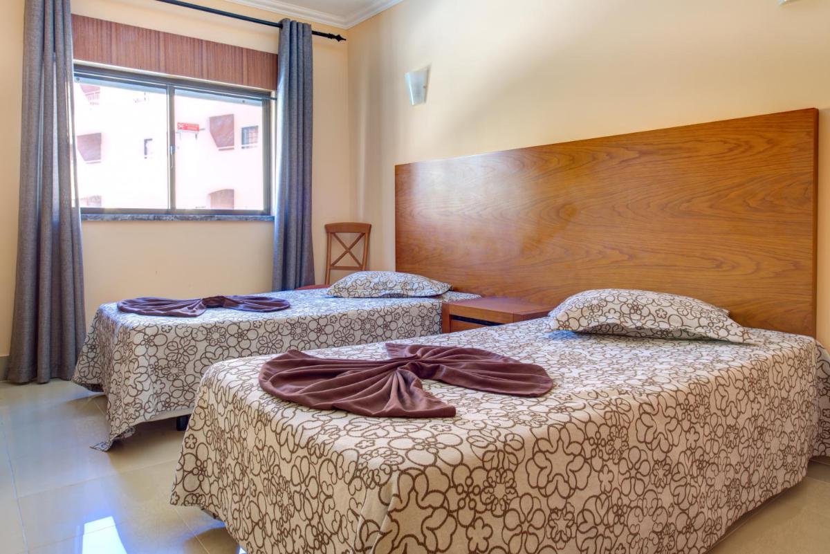um quarto de hotel com duas camas e uma janela em Choromar Apartments em Albufeira